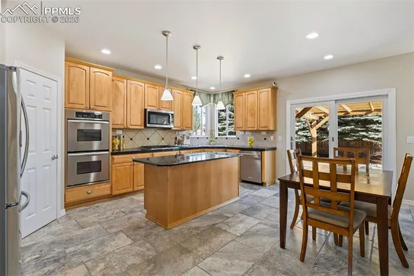 a kitchen with stainless steel appliances granite countertop a stove a sink a microwave a refrigerator and chairs