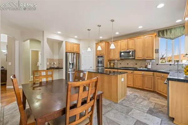 a large kitchen with kitchen island granite countertop a large counter top space a sink appliances and cabinets