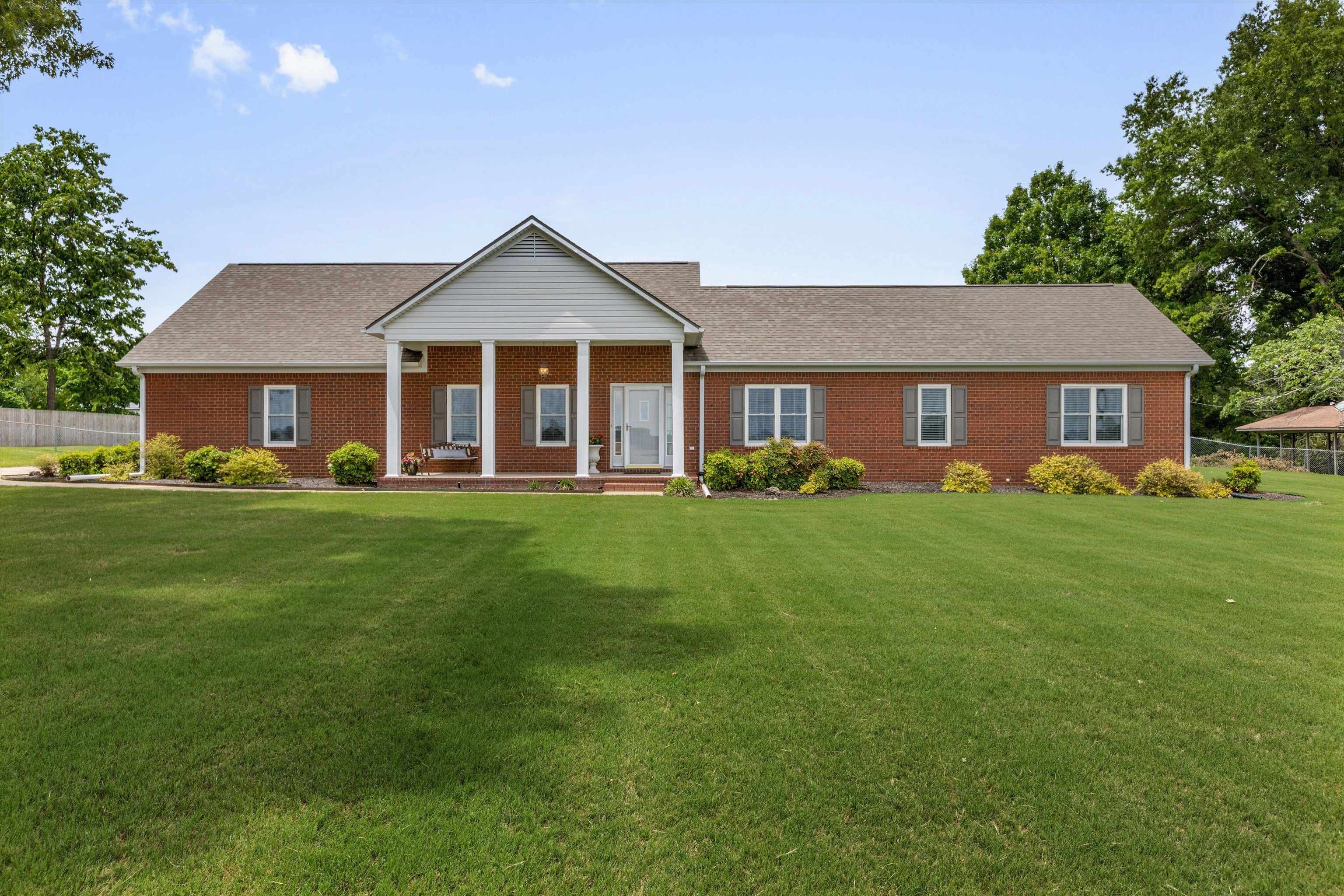 2225 Candy Lane Burlison, TN 38015 - Photo 1 of 27 Brick facade residence featuring a prominent portico with white columns, a gable roofline, and a large front lawn
