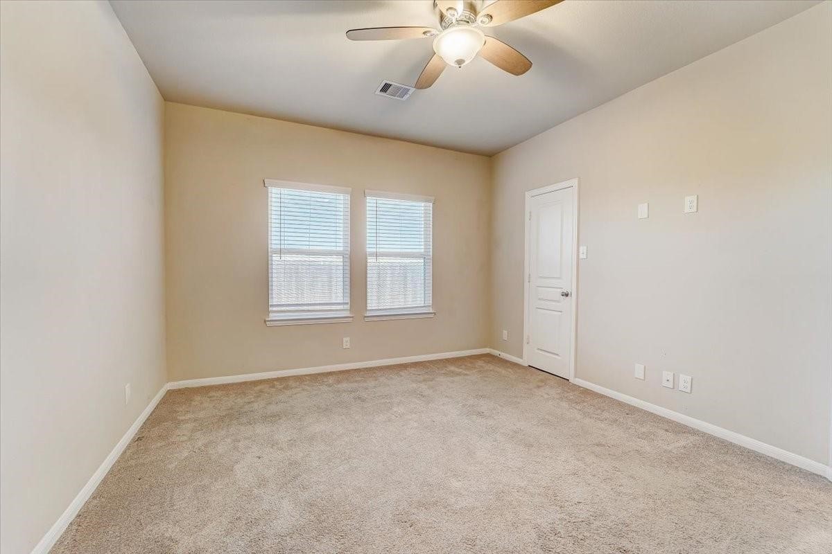 8827 Willet Street Baytown, TX 77521 - Photo 14 of 18 an empty room with a chandelier fan and windows