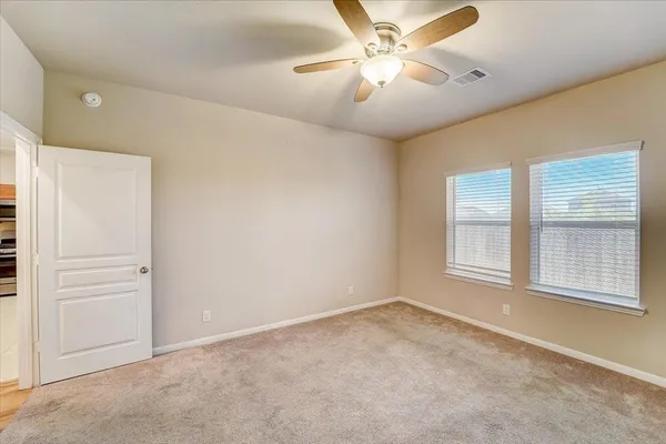 an empty room with windows and fan