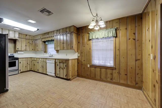 a kitchen with a chandelier a sink cabinets and stainless steel appliances
