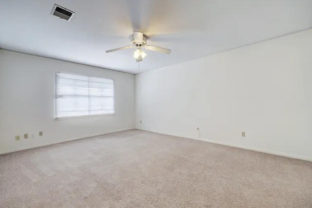 an empty room with a window and a ceiling fan