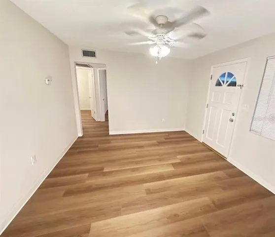 a view of a small space with wooden floor and a chandelier fan