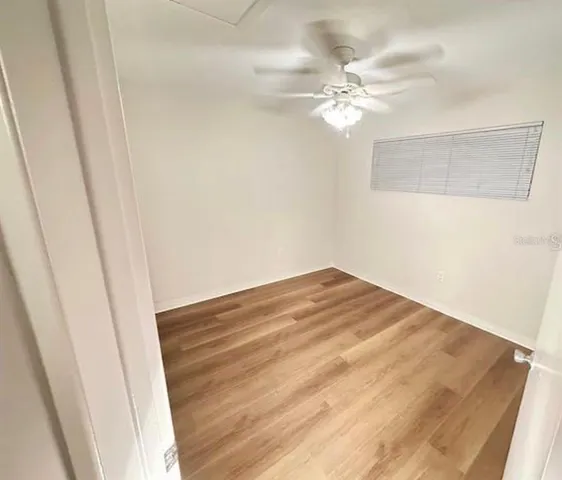 an empty room with wooden floor and fan