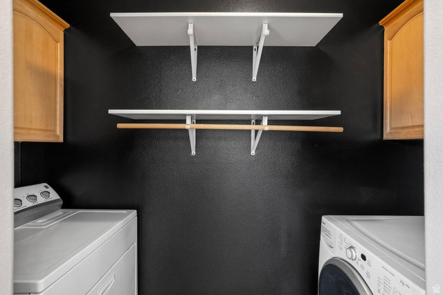 132 Rex Layne Drive Central, UT 84722 - Photo 18 of 39 Laundry area featuring two white shelving units, a wooden hanging rod, and two light wood-finish wall cabinets
