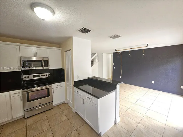 a kitchen with granite countertop a sink and white cabinets