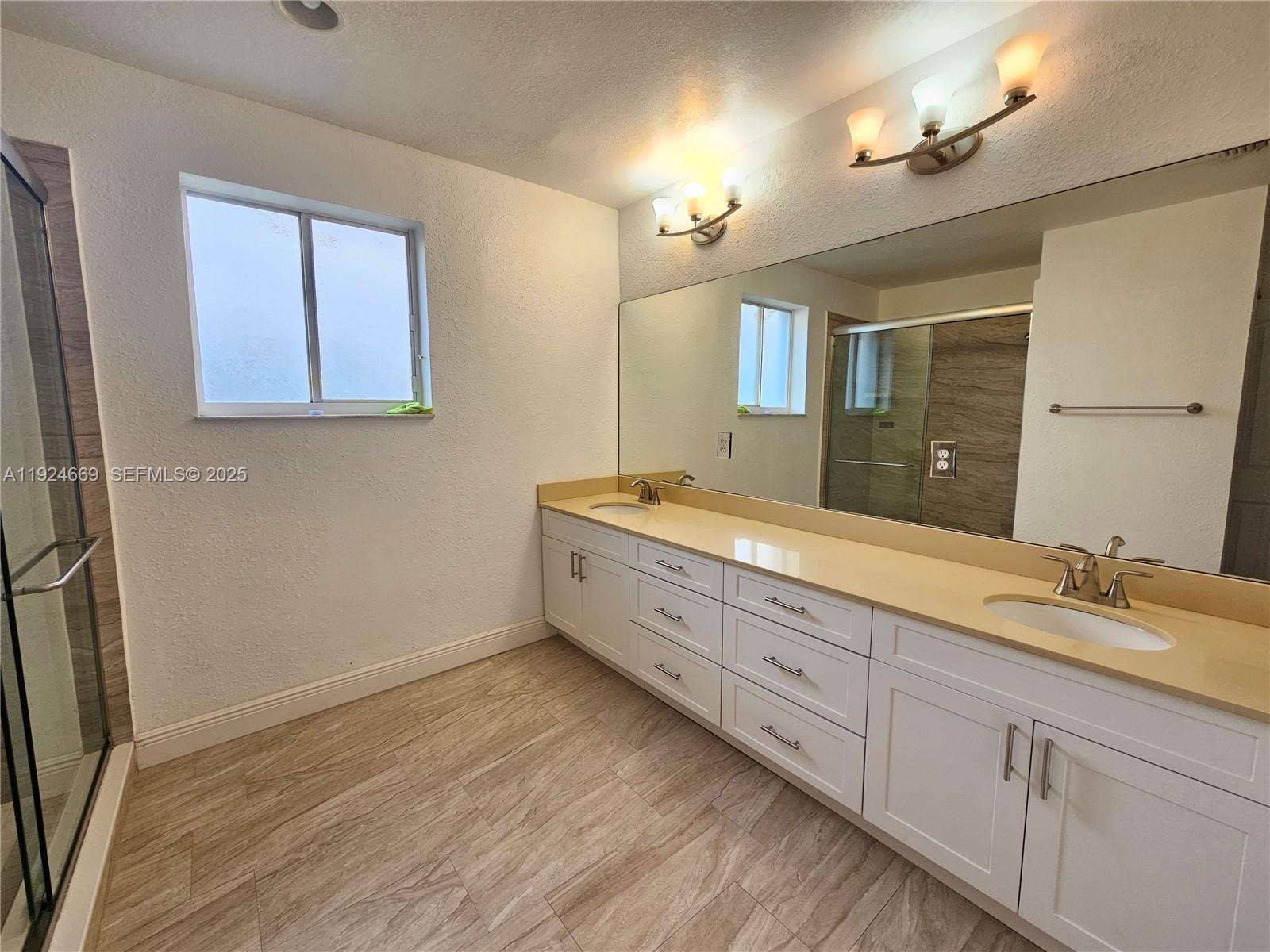 15447 Southwest 151st Street Miami, FL 33196 - Photo 12 of 25 a bathroom with double vanity sink a two mirror a window and a bathtub