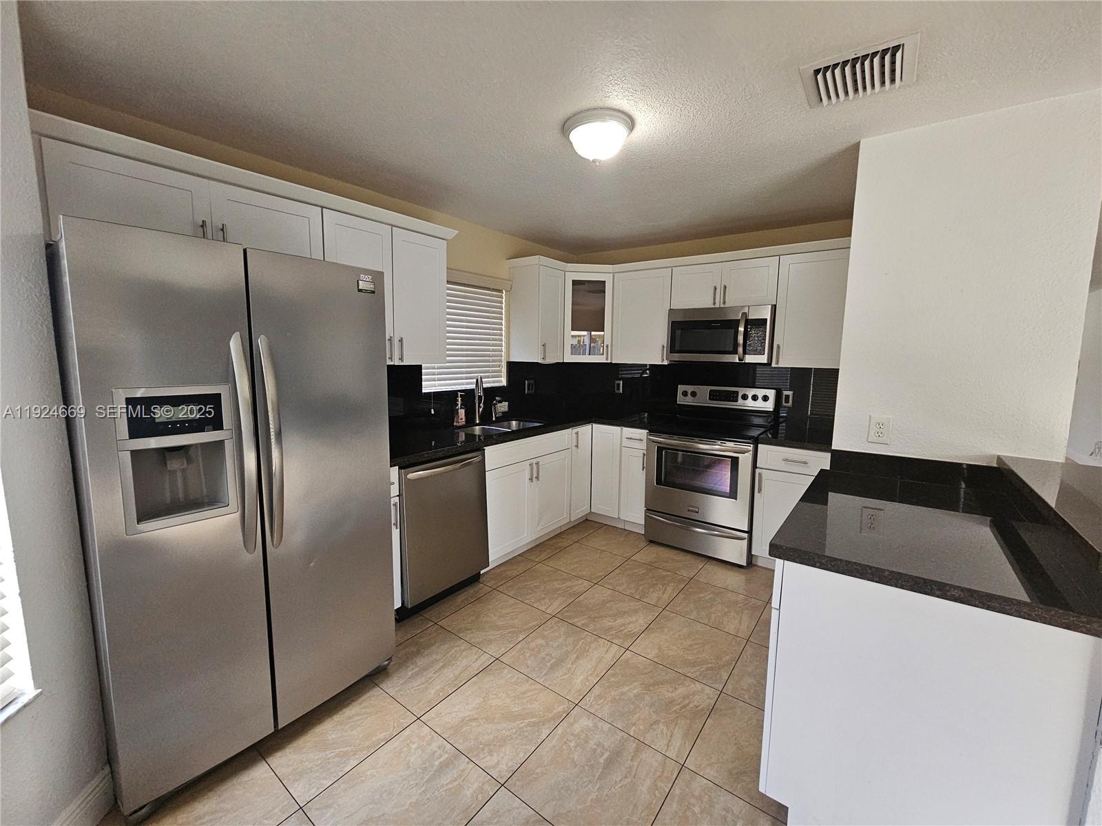 15447 Southwest 151st Street Miami, FL 33196 - Photo 9 of 25 a kitchen with granite countertop a refrigerator and a sink