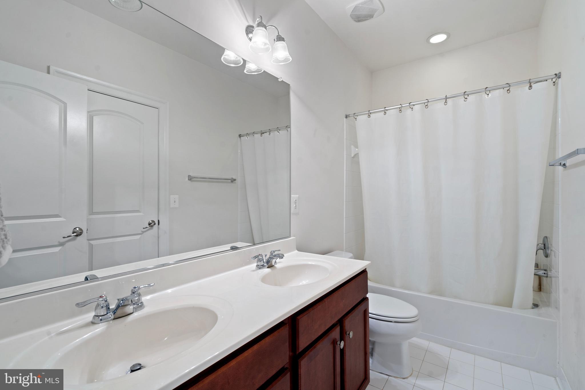 42735 Macauley Place Ashburn, VA 20148 - Photo 28 of 39 a bathroom with a double vanity sink toilet and a mirror