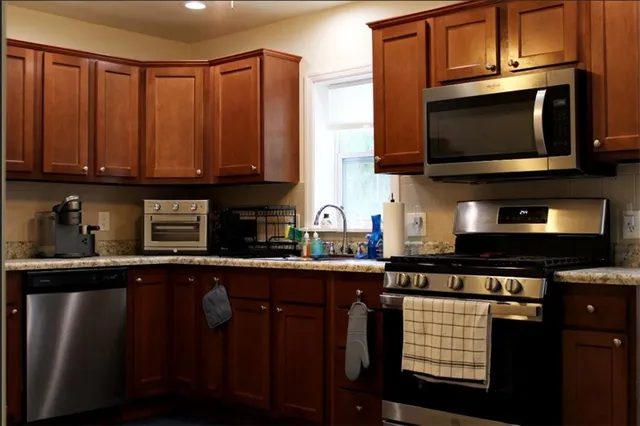 a kitchen with stainless steel appliances wooden cabinets a stove a microwave and a sink