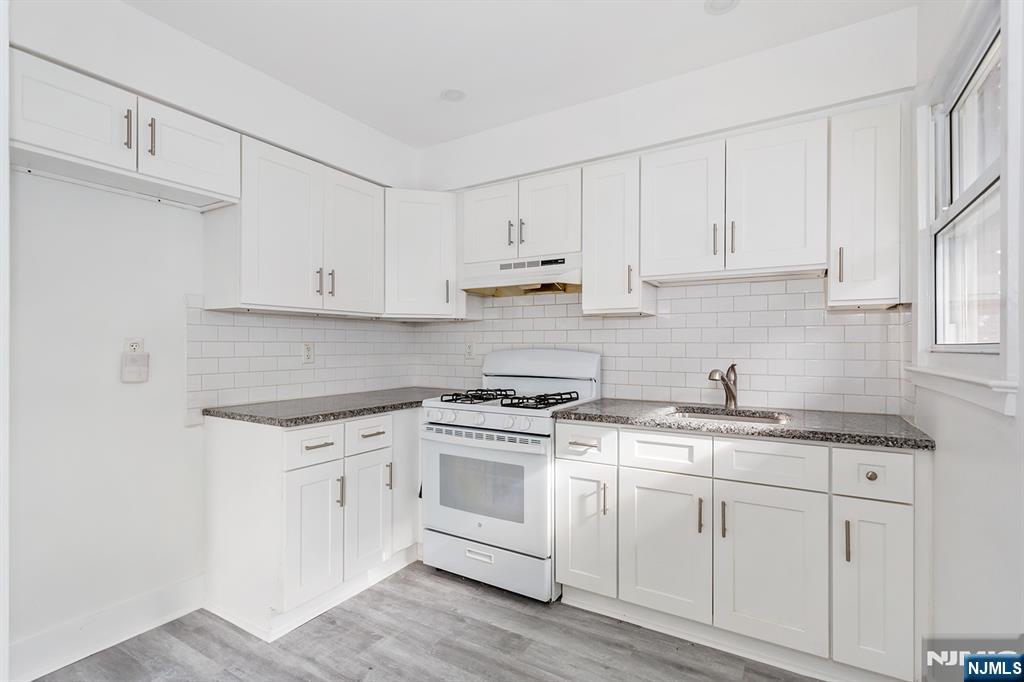 a kitchen with granite countertop white cabinets and white appliances
