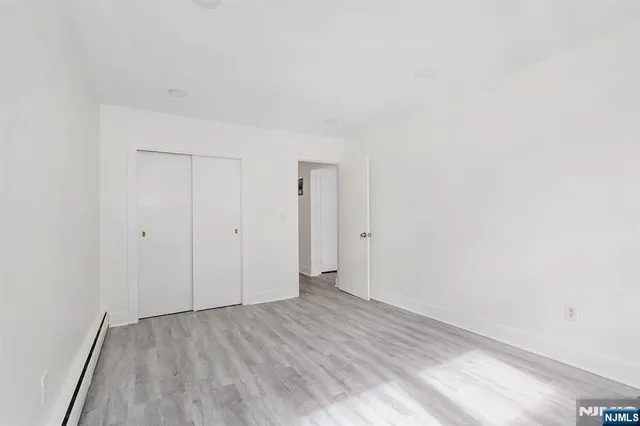 a view of an empty room with wooden floor and closet