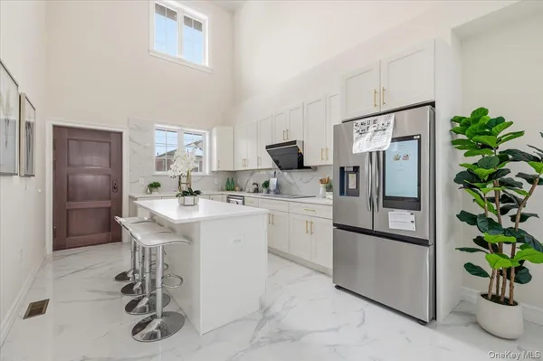 a kitchen with stainless steel appliances a refrigerator a sink a stove and white cabinets