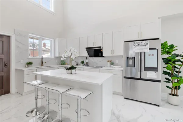 a kitchen with stainless steel appliances a refrigerator a sink a stove and white cabinets