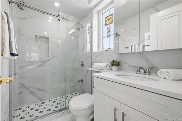 a bathroom with a granite countertop sink toilet and shower