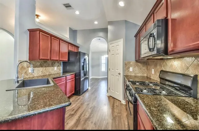 a kitchen with stainless steel appliances granite countertop a stove a sink and a microwave