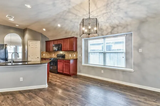 a open kitchen with stainless steel appliances granite countertop a sink a stove and a wooden floors