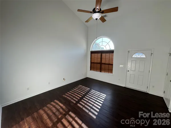 an empty room with wooden floor cabinet and windows