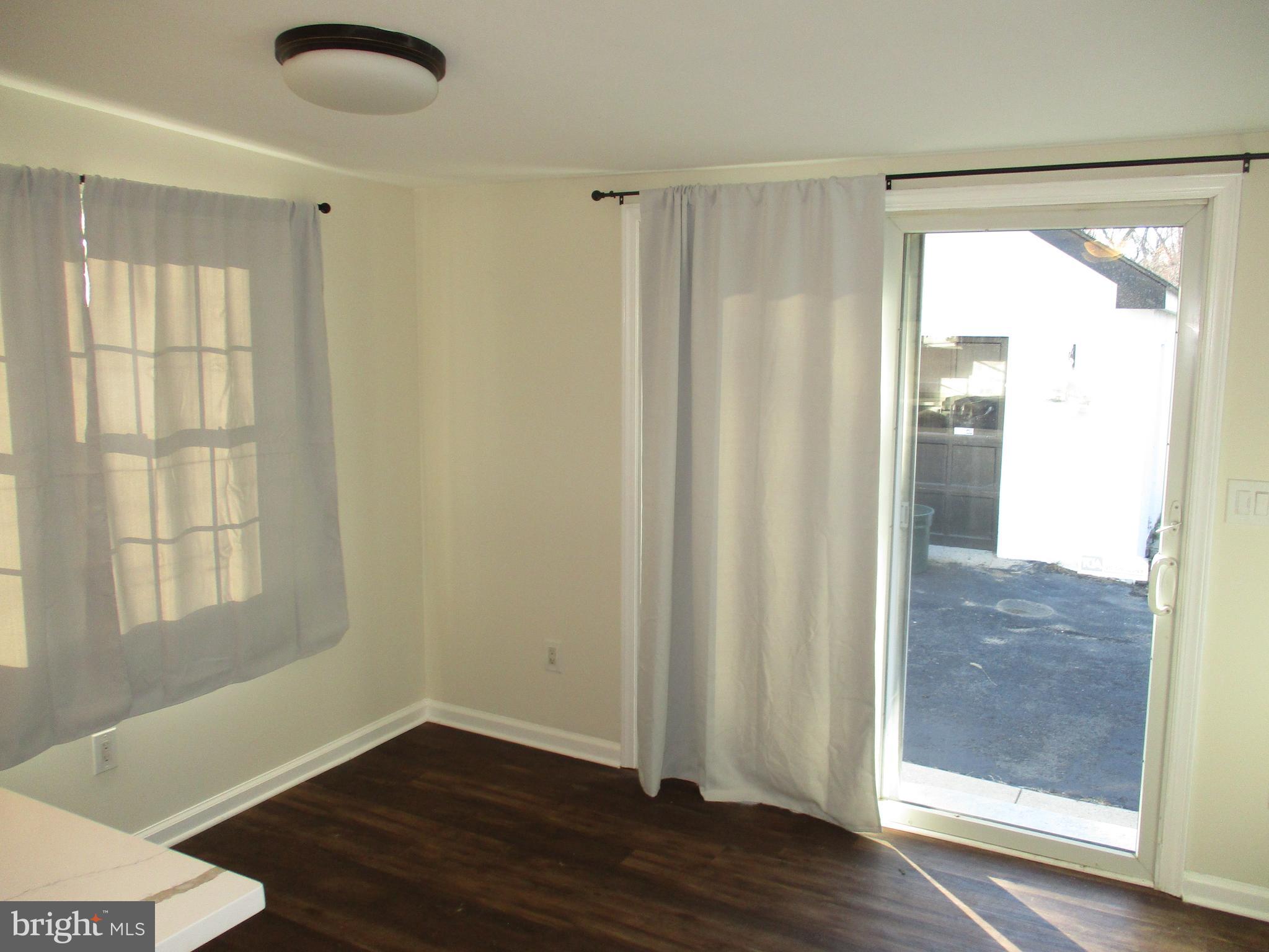 121 Hoover Avenue Hamilton, NJ 08619 - Photo 5 of 12 an empty room with wooden floor and windows