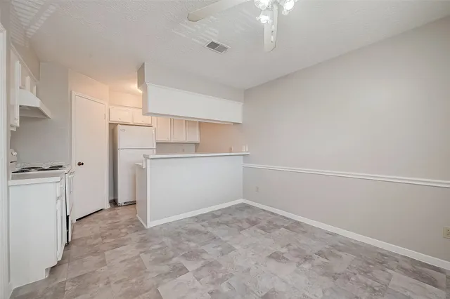 a view of a kitchen with a sink and dishwasher a refrigerator with white cabinets