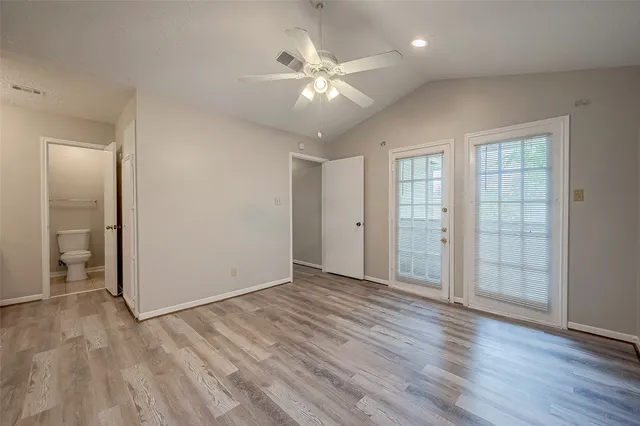 an empty room with wooden floor and ceiling fan