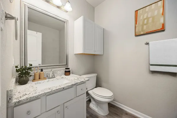 a bathroom with a granite countertop sink a toilet and mirror