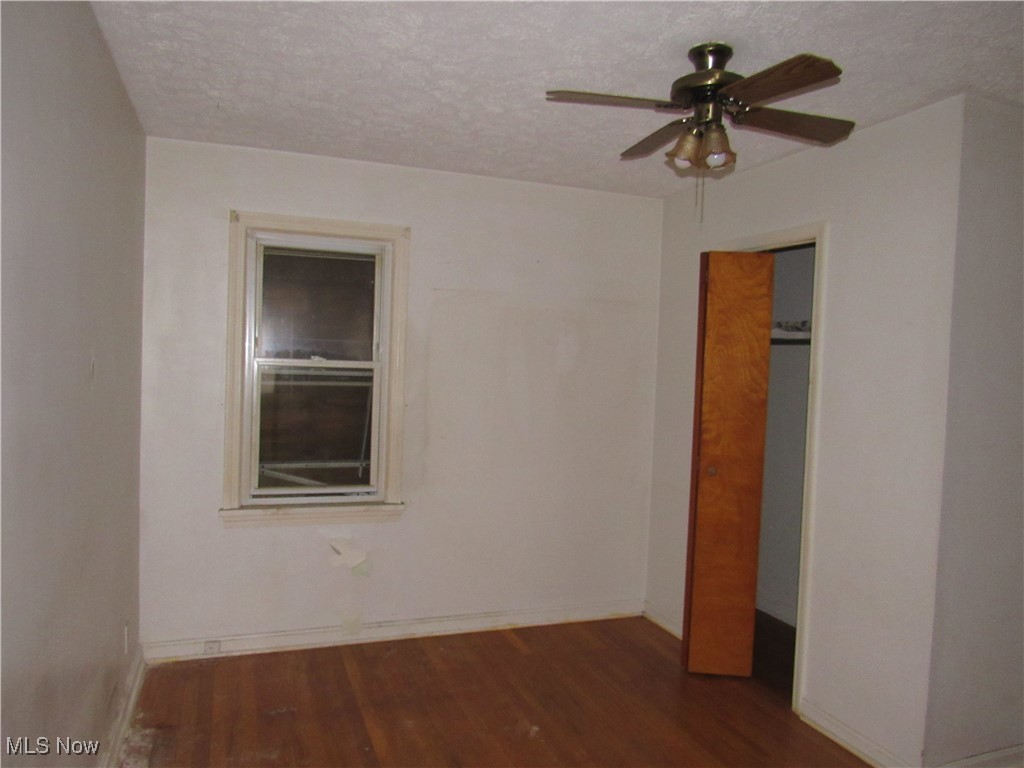 4550 Effie Road Cleveland, OH 44105 - Photo 14 of 29 Unfurnished bedroom with dark wood-style floors, ceiling fan, a textured ceiling, and a closet