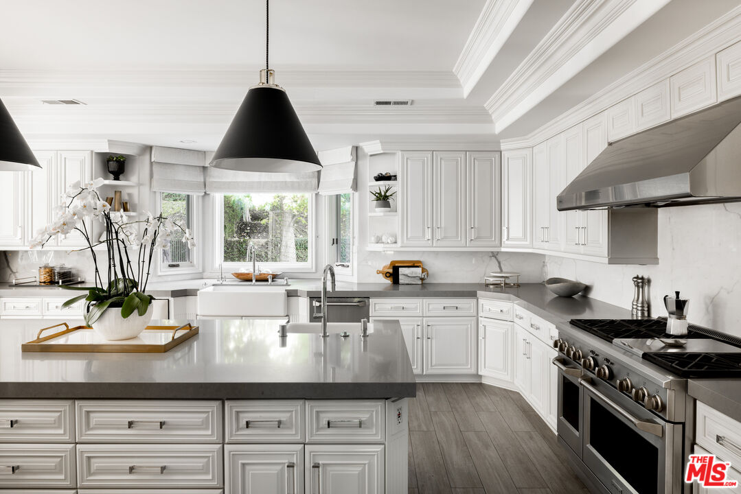 11972 Lockridge Road Studio City, CA 91604 - Photo 8 of 29 a kitchen with a sink dishwasher a stove a dining table and chairs with wooden floor