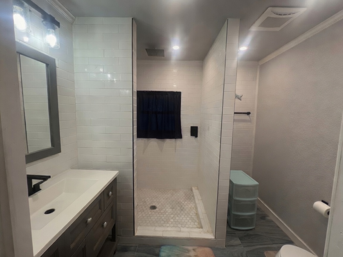 107 West 7th Street Elgin, TX 78621 - Photo 5 of 11 Updated bathroom with a spacious walk-in shower and a modern vanity with ample counter space.