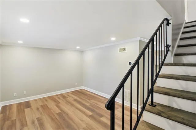 a view of an empty room with wooden floor and stairs