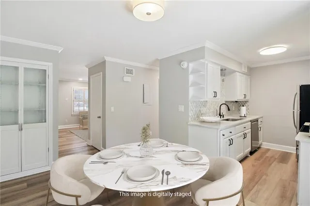 a kitchen with white cabinets a sink dining table and chairs