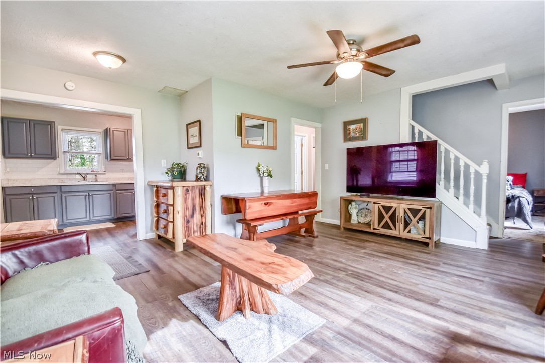 1969 Paisley Road Madison, OH 44057 - Photo 5 of 20 Spacious living area featuring wood-finish flooring, a ceiling fan with integrated lighting, and a white balustrade staircase