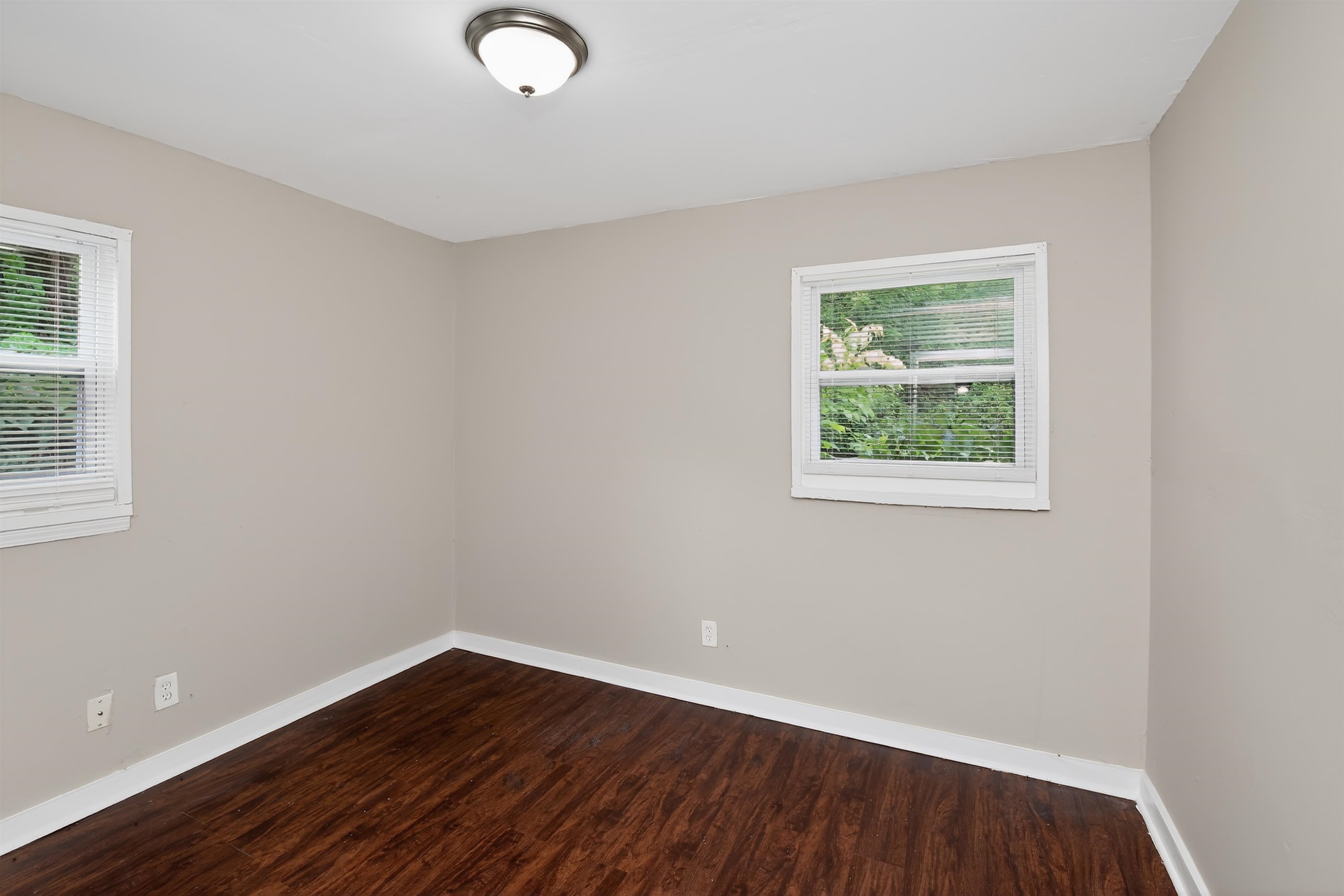 4838 Manson Road Memphis, TN 38109 - Photo 9 of 28 Room featuring wood-finish flooring, neutral wall paint, white trim, two windows with blinds, and a ceiling-mounted light fixture