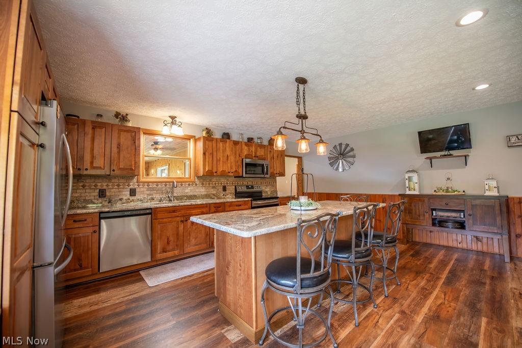 48800 Foxes Bottom Road Cadiz, OH 43907 - Photo 27 of 50 Kitchen area featuring wood cabinetry, stone countertops, stainless steel appliances, and a central island with seating