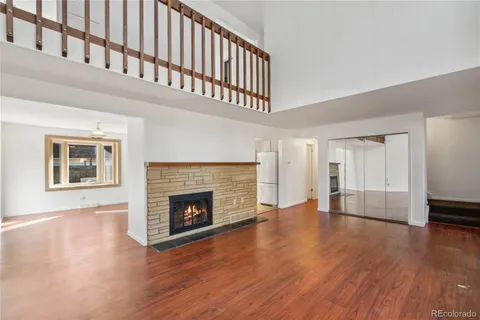 a view of an empty room with wooden floor fireplace and a window