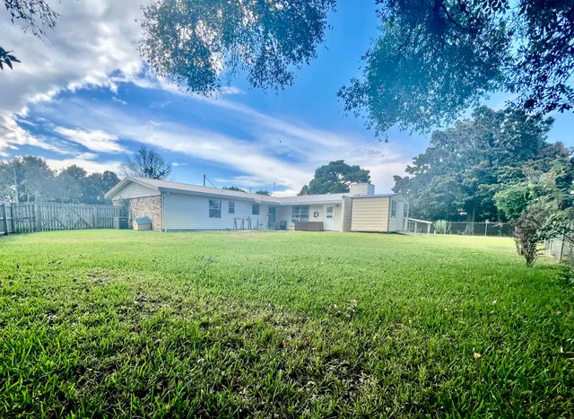 a view of a house with backyard and a tree