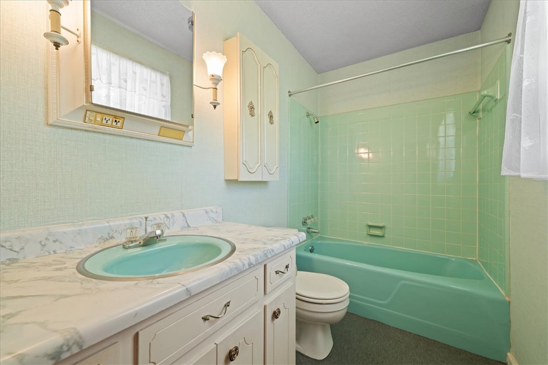 304 Shaw Road Honea Path, SC 29654 - Photo 26 of 39 This bathroom features a single vanity, a toilet, and a bathtub with tiled walls.