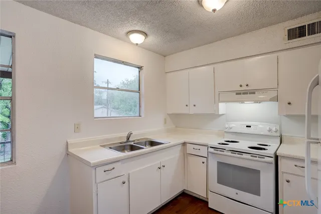 a kitchen with granite countertop white cabinets and white appliances
