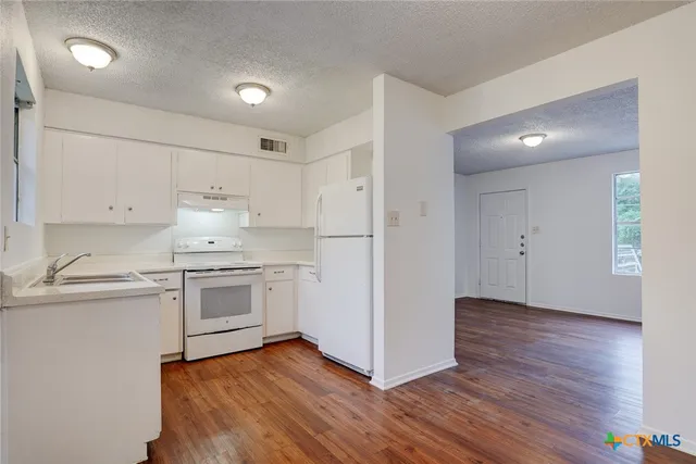 a kitchen with granite countertop white cabinets and white appliances