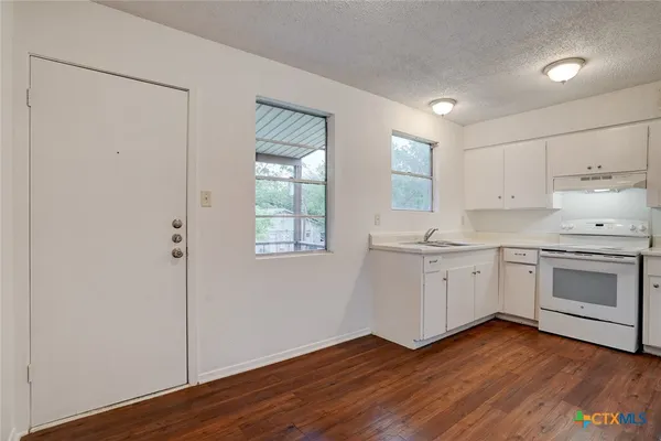 a kitchen with wooden floors and white appliances