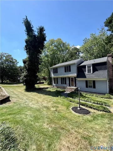 a front view of house with yard and trees in the background