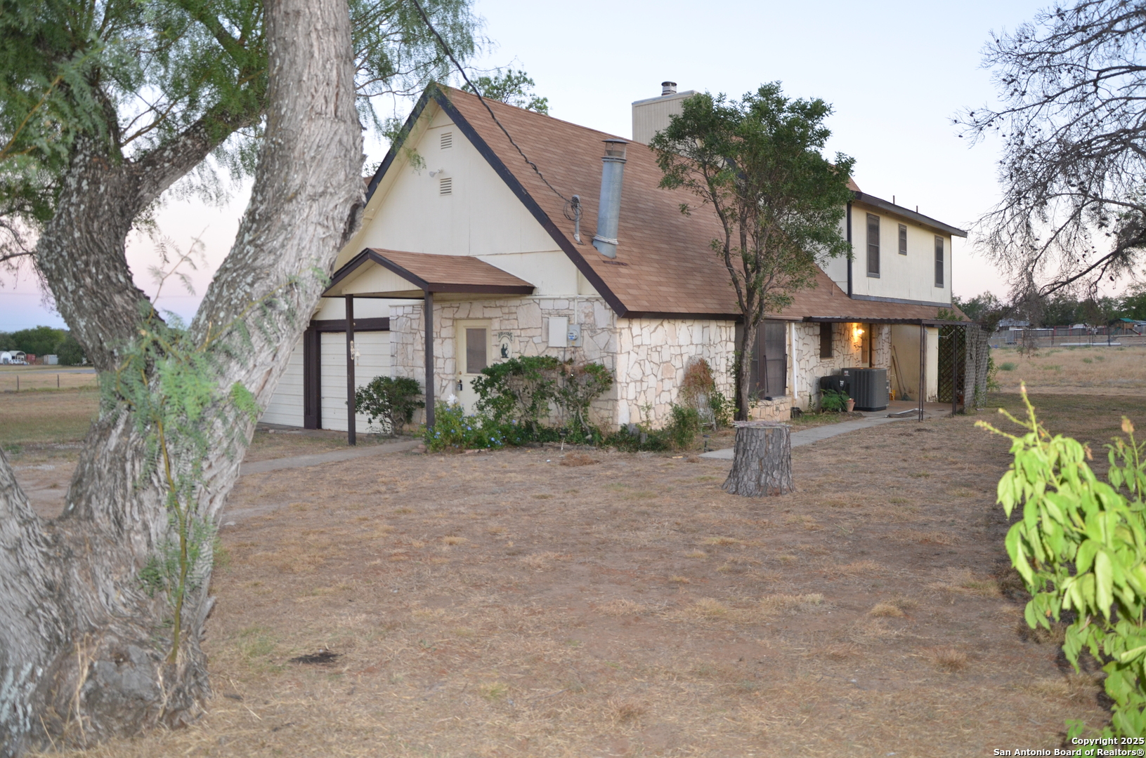 115 B Littleton Drive Devine, TX 78016 - Photo 22 of 27 a front view of a house with a yard and a garden