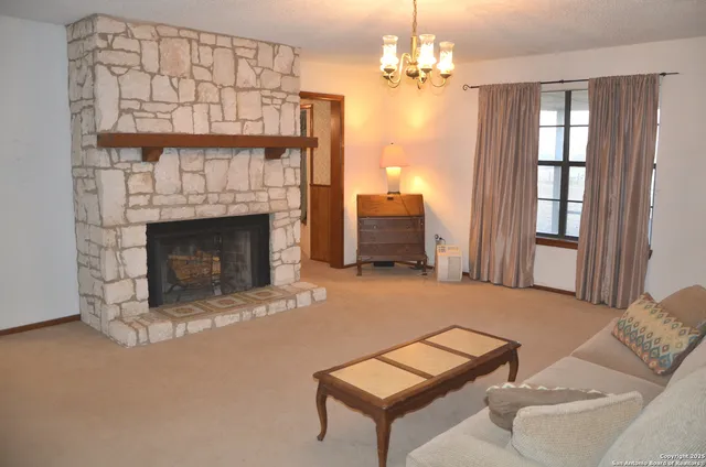 a living room with furniture a fireplace and a chandelier