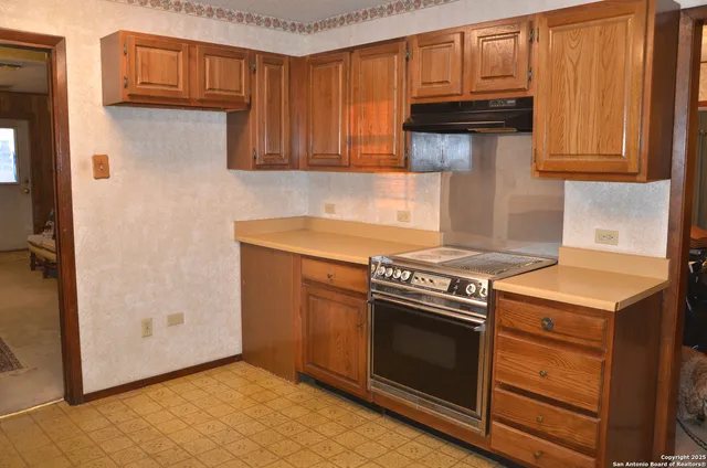 a kitchen with granite countertop a stove top oven microwave and cabinets