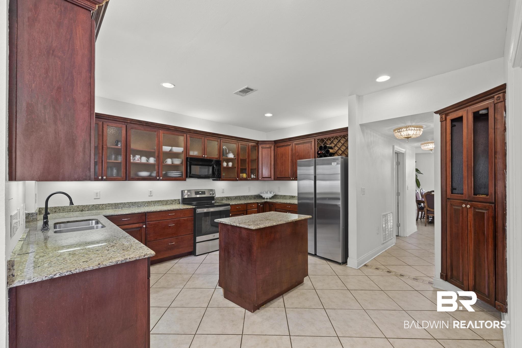 32875 Faircloth Road Lillian, AL 36549 - Photo 21 of 85 Kitchen with light stone countertops, stainless steel appliances, glass insert cabinets, a center island, and light tile patterned flooring