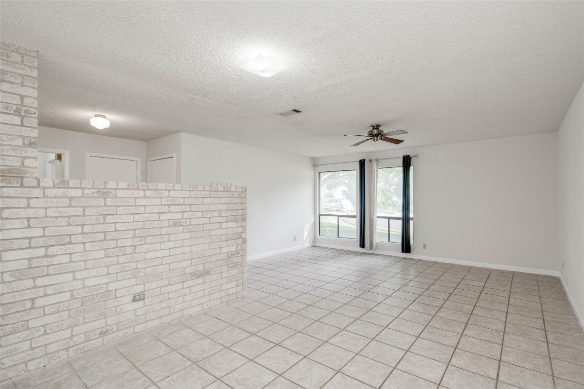 1402 Meadgreen Circle Austin, TX 78758 - Photo 15 of 35 Unfurnished room with a textured ceiling, a ceiling fan, and light tile patterned floors