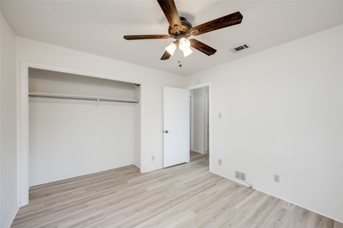 1402 Meadgreen Circle Austin, TX 78758 - Photo 17 of 35 Unfurnished bedroom featuring light wood finished floors, ceiling fan, and a closet