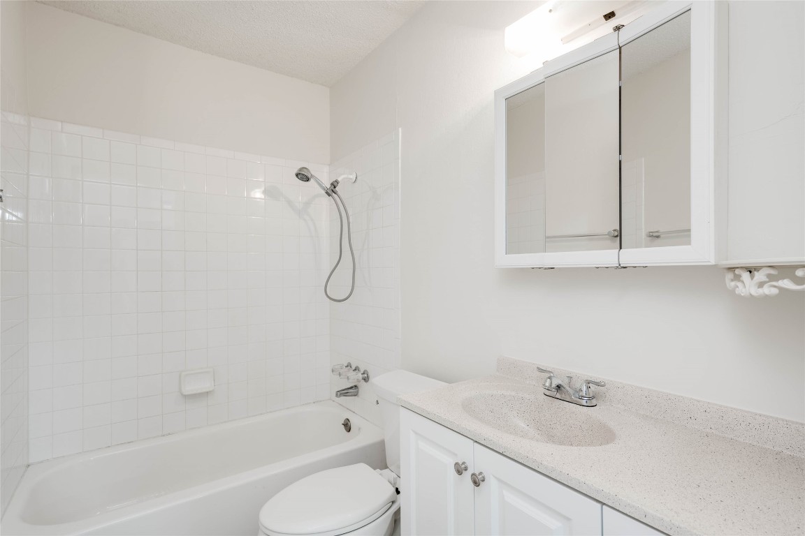1402 Meadgreen Circle Austin, TX 78758 - Photo 19 of 35 Bathroom featuring vanity, bathtub / shower combination, and a textured ceiling