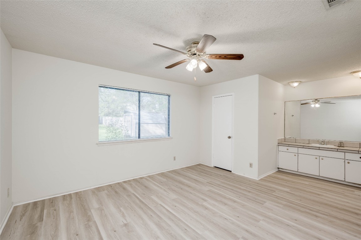 1402 Meadgreen Circle Austin, TX 78758 - Photo 20 of 35 Unfurnished bedroom featuring light wood-style flooring, a textured ceiling, and ceiling fan
